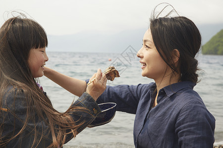 女孩喂妈妈吃东西在海边图片