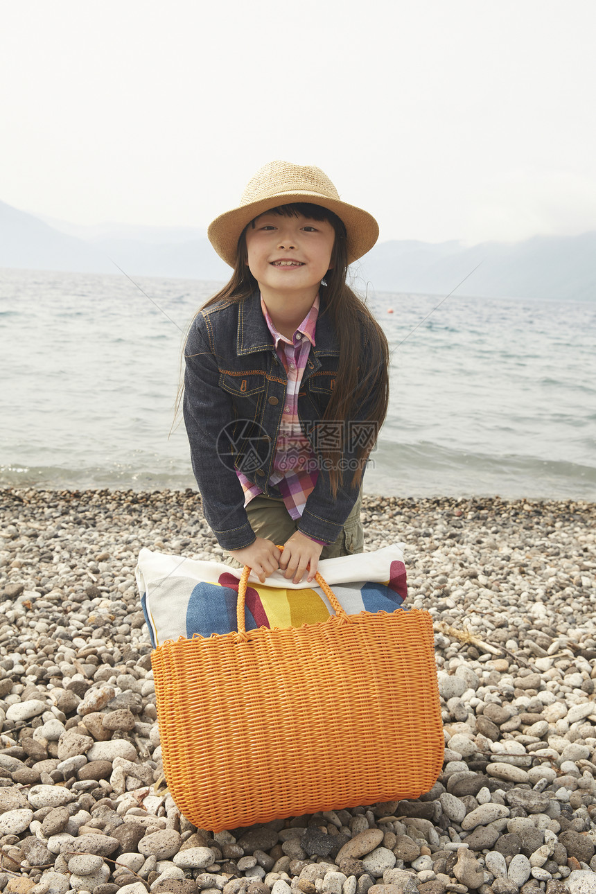 女孩拿着野餐包在海边图片