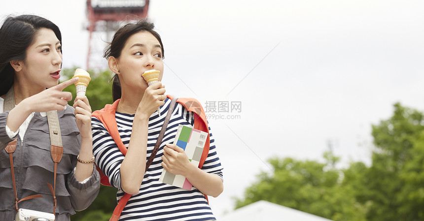 吃冰激凌带着相机旅行的2个女性图片