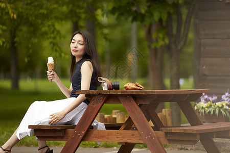 拿着冰淇淋坐在木椅子上的成熟女性在思考高清图片