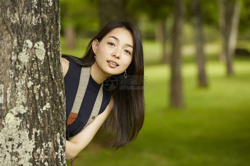 在树旁伸出头来的成熟女性图片