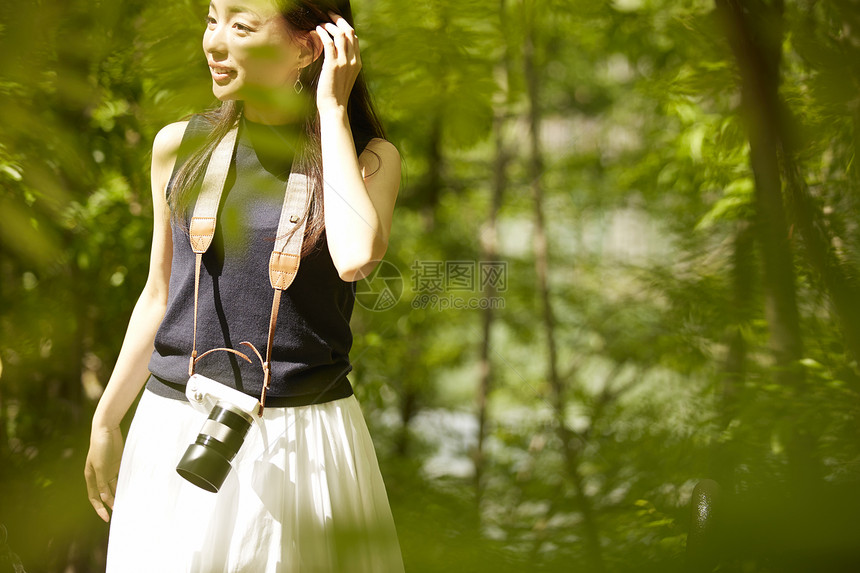 带着相机在树林间行走的女性图片