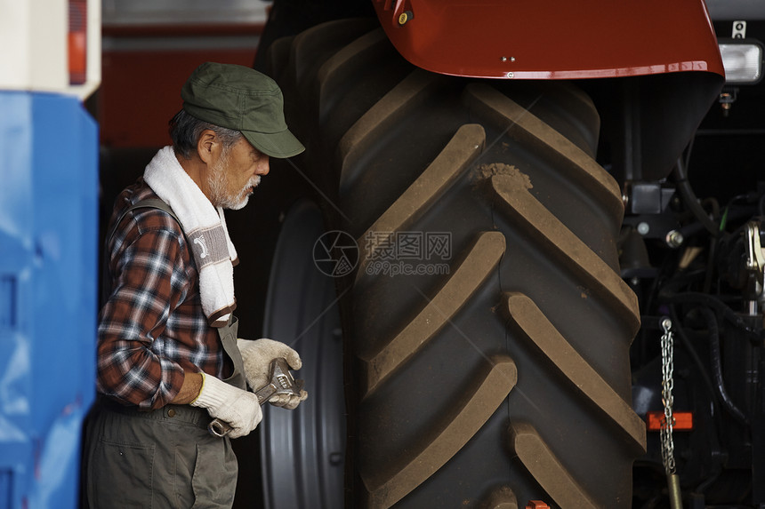 农夫检查拖拉机轮胎图片