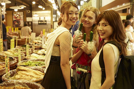 年轻美女带友人当地市场旅游观光形象背景图片