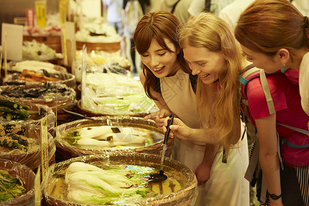 年轻美女带外国友人体验当地美食背景图片