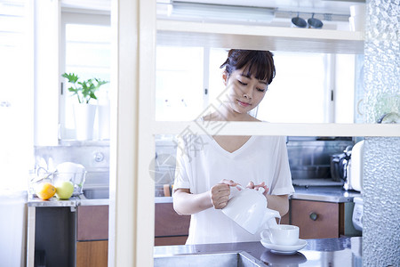 在厨房倒茶的女性图片