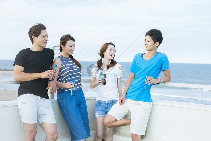 在海边喝酒谈天的青年人图片