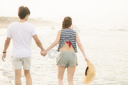 海滩边散步的情侣背影图片