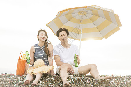 情侣坐在海滩上喝酒聊天图片