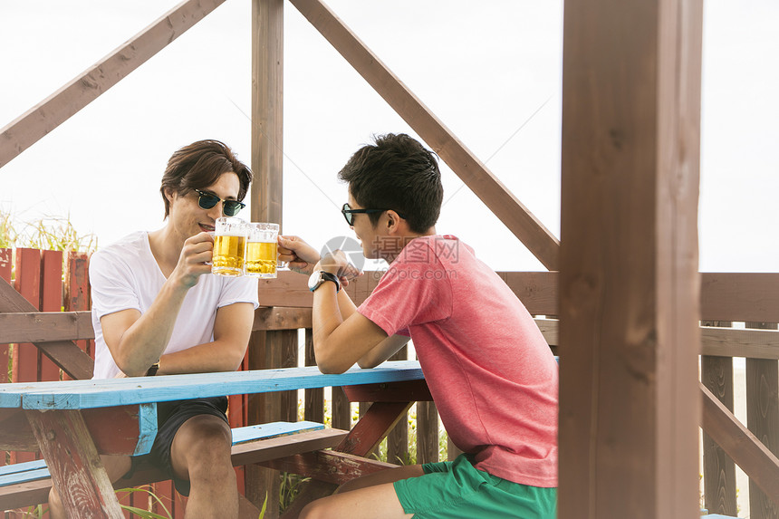 2个男性夏日海边喝酒聊天图片