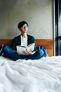 坐在床上看书的男性图片