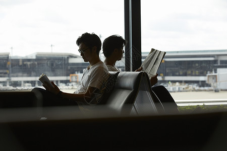 两个男人坐在候机厅看报纸图片素材