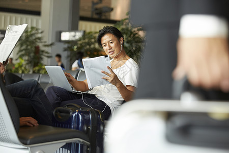 在机场候机厅拿着笔记本电脑工作的男性图片