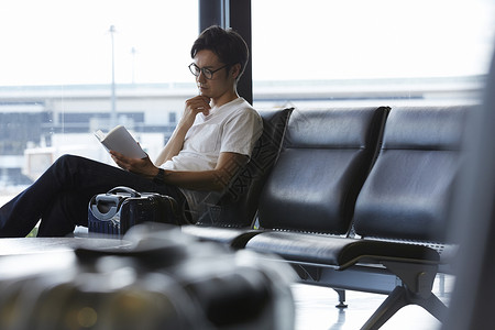 一个在机场等候看书的男性图片