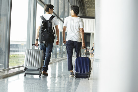 两个男人拖着行李箱走在机场大厅图片素材