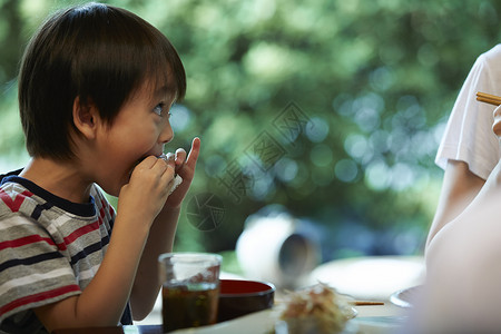 围坐在餐桌前吃饭的小男孩背景图片