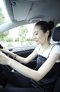 车与音乐素材假日二十几岁女子戴着耳机开车背景