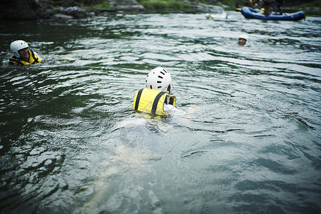穿着救生衣在水里浮着的年轻人户外高清图片素材