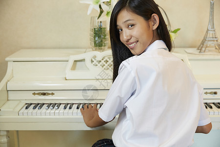 在客厅转头微笑的弹钢琴的女学生背景图片