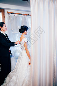 婚纱店试穿婚纱的新娘与婚礼策划师背景图片
