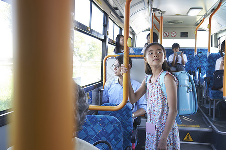 公共汽车扶着护栏站着的小学生女孩高清图片素材