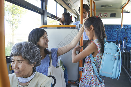 妈妈和女儿一起乘坐公交车通勤高清图片素材