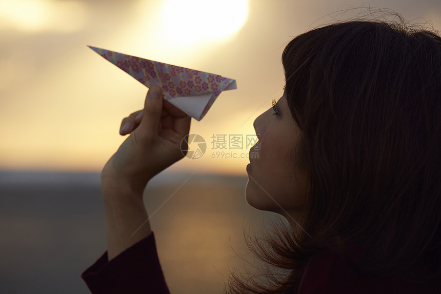 女人在夕阳下手拿纸飞机图片