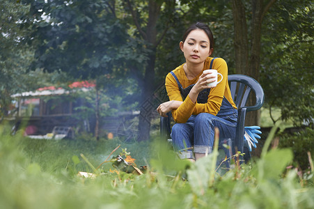 在篝火旁拿着杯子的女人图片