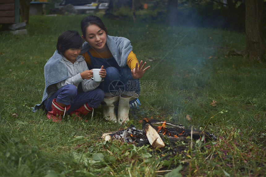 蹲在篝火旁取暖的母子二人图片