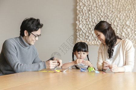 一家三口坐在桌前玩亲子游戏高清图片
