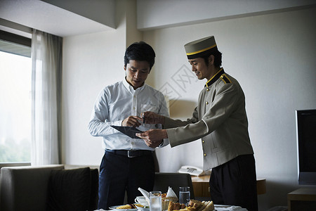 酒店男服务员在酒店房间里给服务生付早餐费的商务人士背景