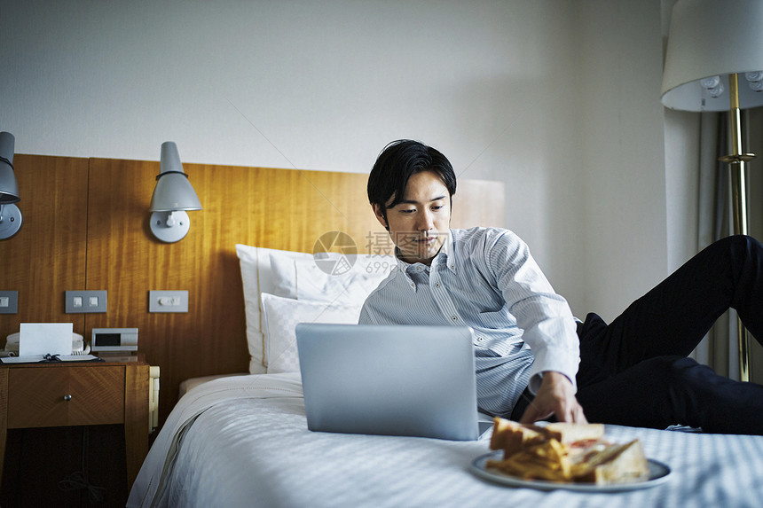 在酒店床上吃早餐的商务男子图片