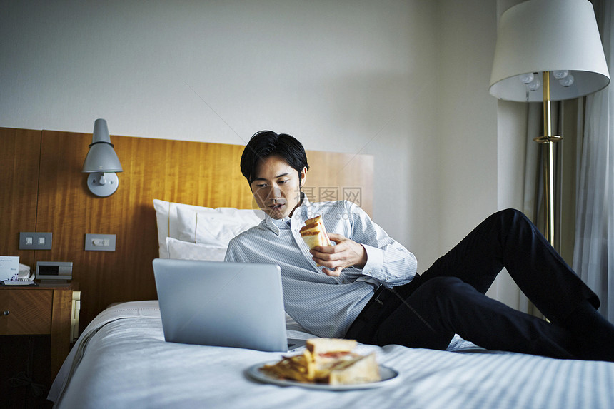 商务人士放松的在酒店床上吃早饭图片