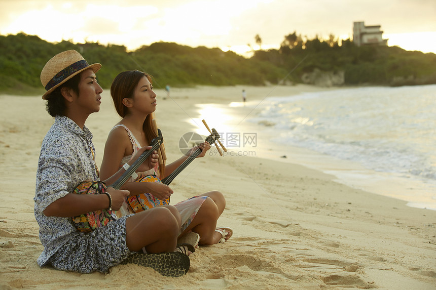   海边弹吉他的男性和女性图片