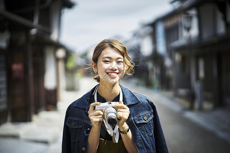 手拿相机开心微笑的旅游女孩图片