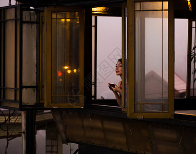 女人在茶馆窗台边喝茶夜市高清图片素材