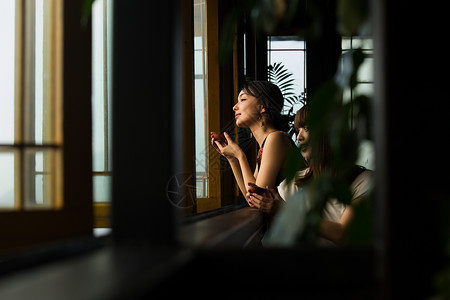 女人在茶馆窗台边品茶看窗外快乐的高清图片素材