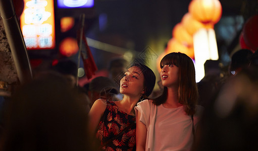 在夜市和朋友一起逛街的女游客休息高清图片素材