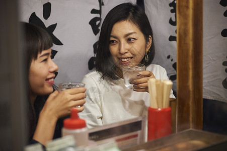 喝清酒吃烧烤的女游客福冈夜晚高清图片素材