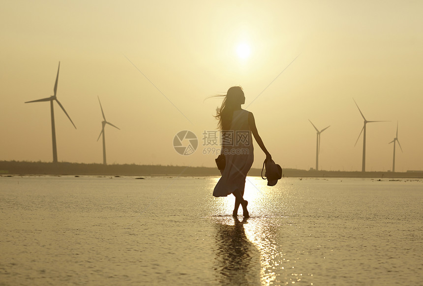 日落时分走在海滩边上长裙美女图片