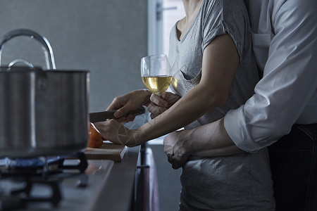 端着酒杯的男人搂着切菜的女人图片