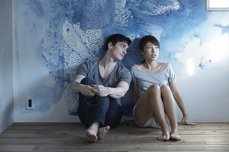 蓝色墙壁前坐着的情侣看窗外图片