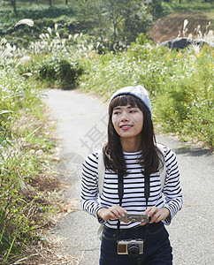 在田间小路散步的女人拿着花手机图片