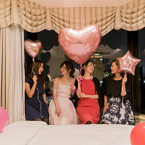 朋友聚会女人们在卧室拿着气球两两对视图片