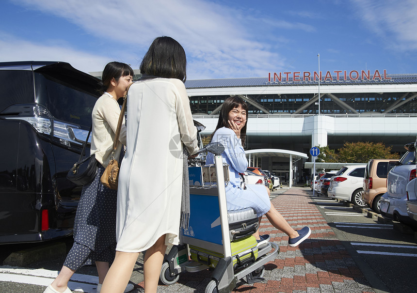 在机场停车场推着行李和朋友走的女人图片