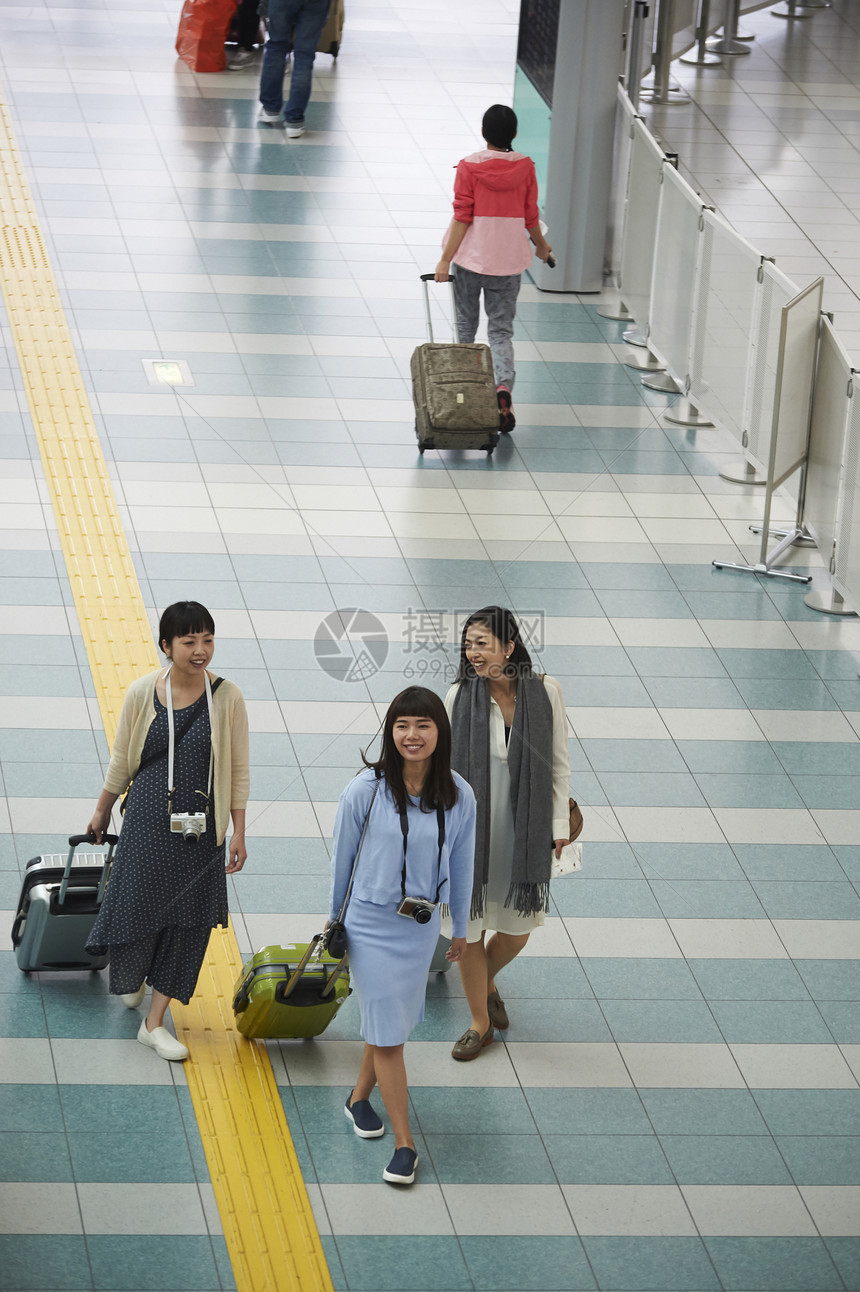 女生拖着行李走在机场图片