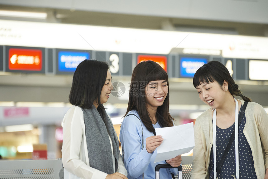 拿着行李走在航空站的女人们图片