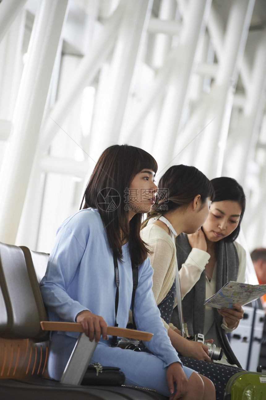 拿着行李坐在航空站候车室椅子上的女人们图片