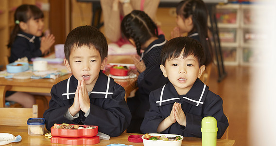 午饭时间在餐桌前双手合十的小男孩图片