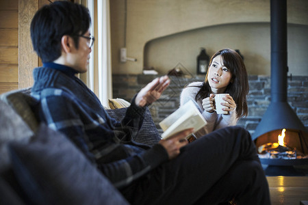 在小屋壁炉边女人和拿着书的男人说笑轻井泽两个人高清图片素材